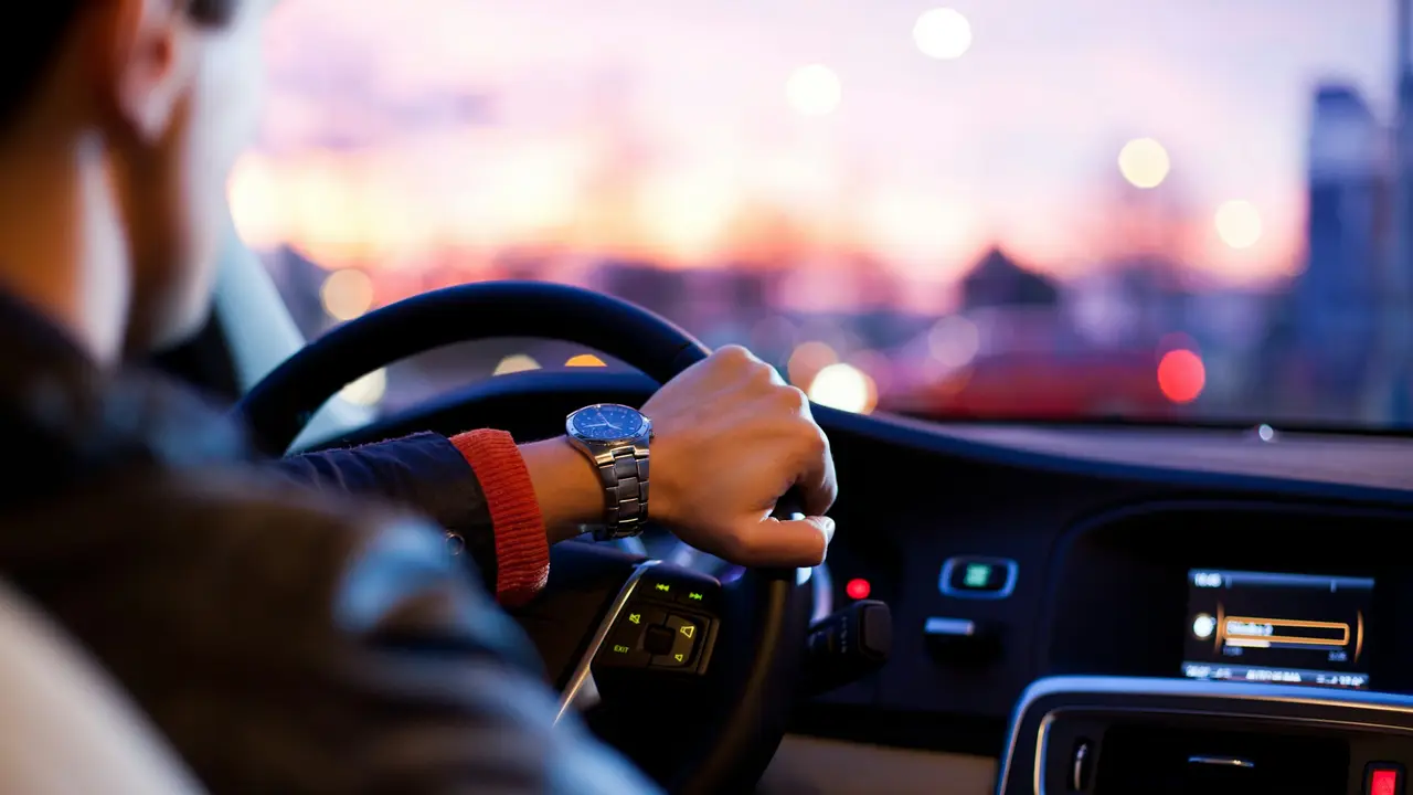 Hände am Lenkrad eines Fahrzeugs bei Abendlicht