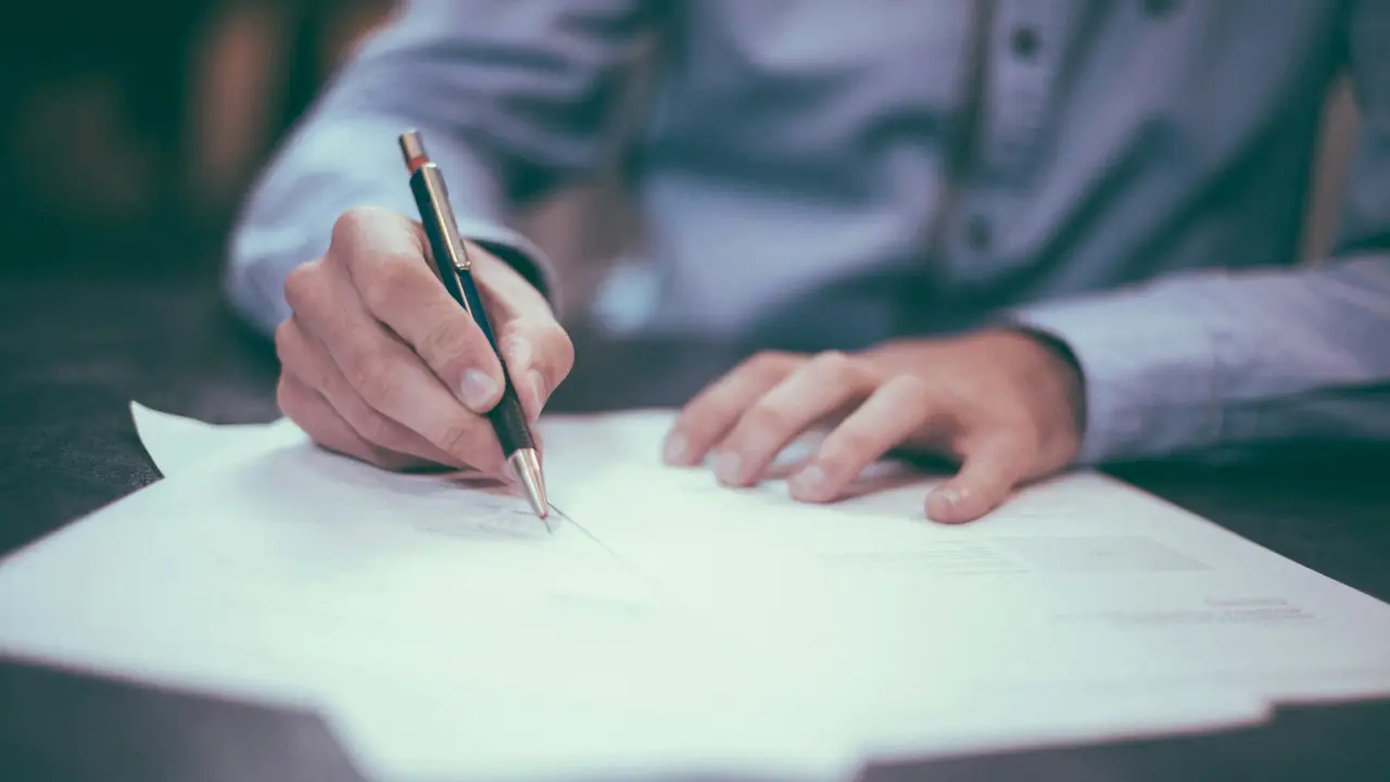 Hand mit Stift beim Ausfüllen von Unterlagen