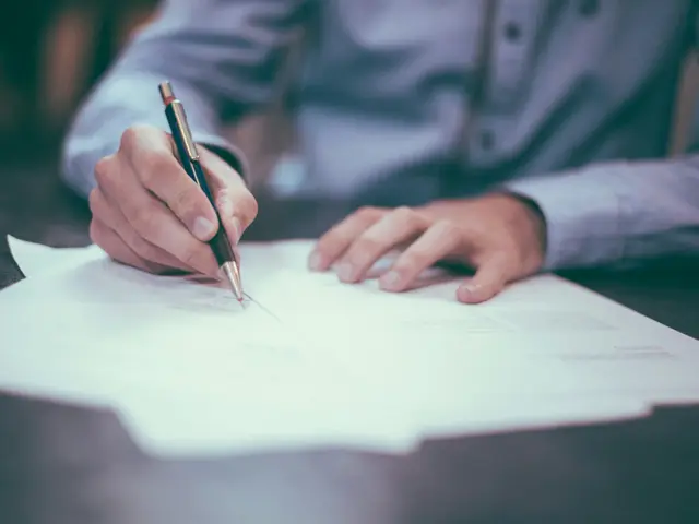 Hand mit Stift beim Ausfüllen von Unterlagen